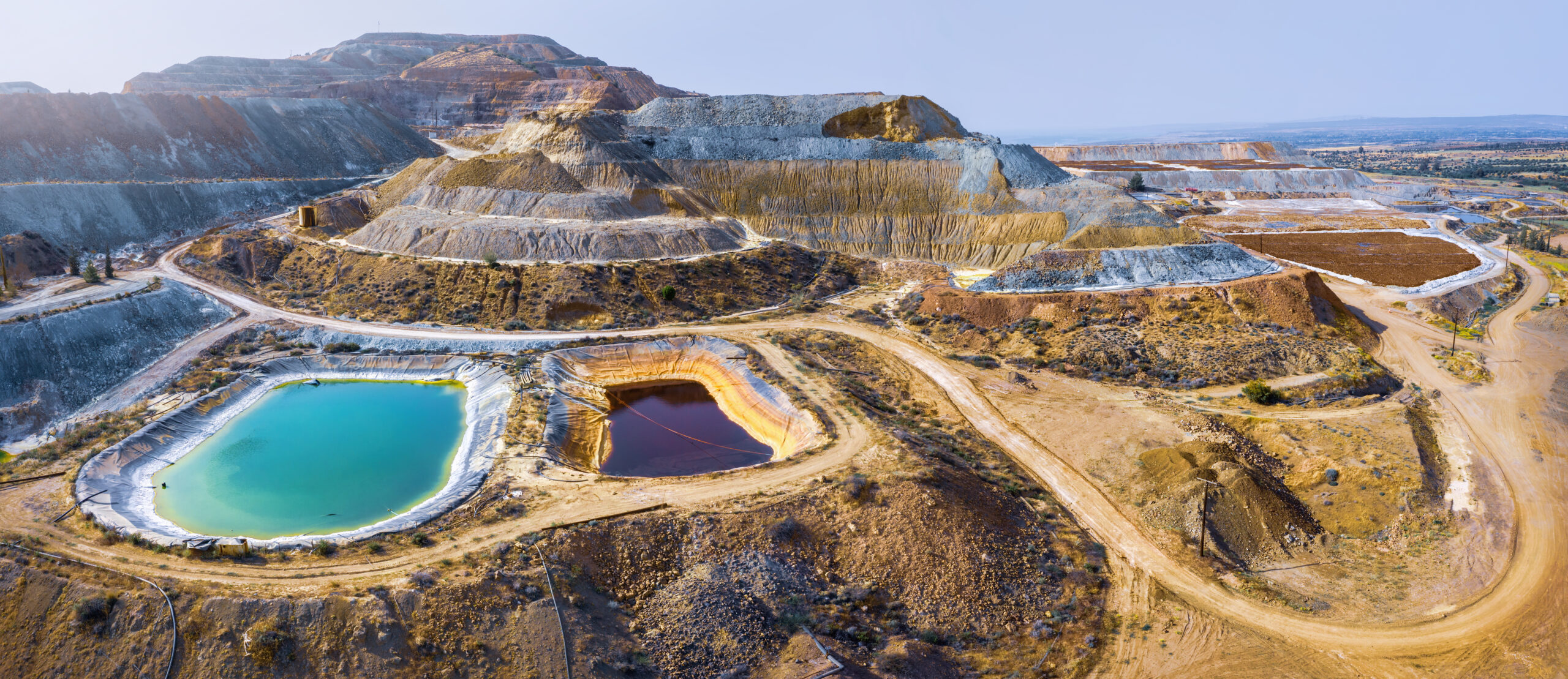 Copper mining with lake in mine pit and spoil heaps covered with pine trees.